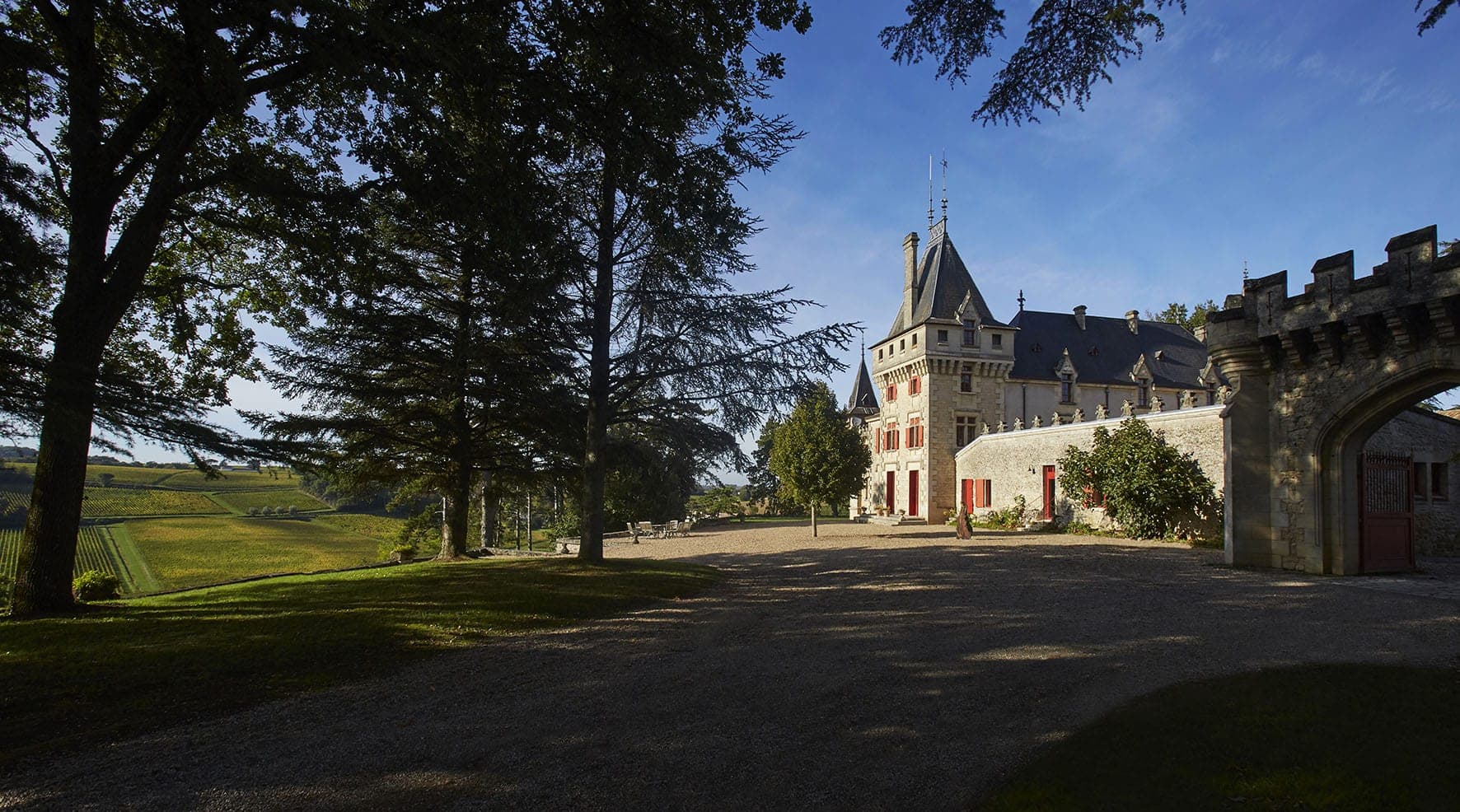Die Westfassade von Château de Pressac, rechts das Tor, links die Reben am Hang