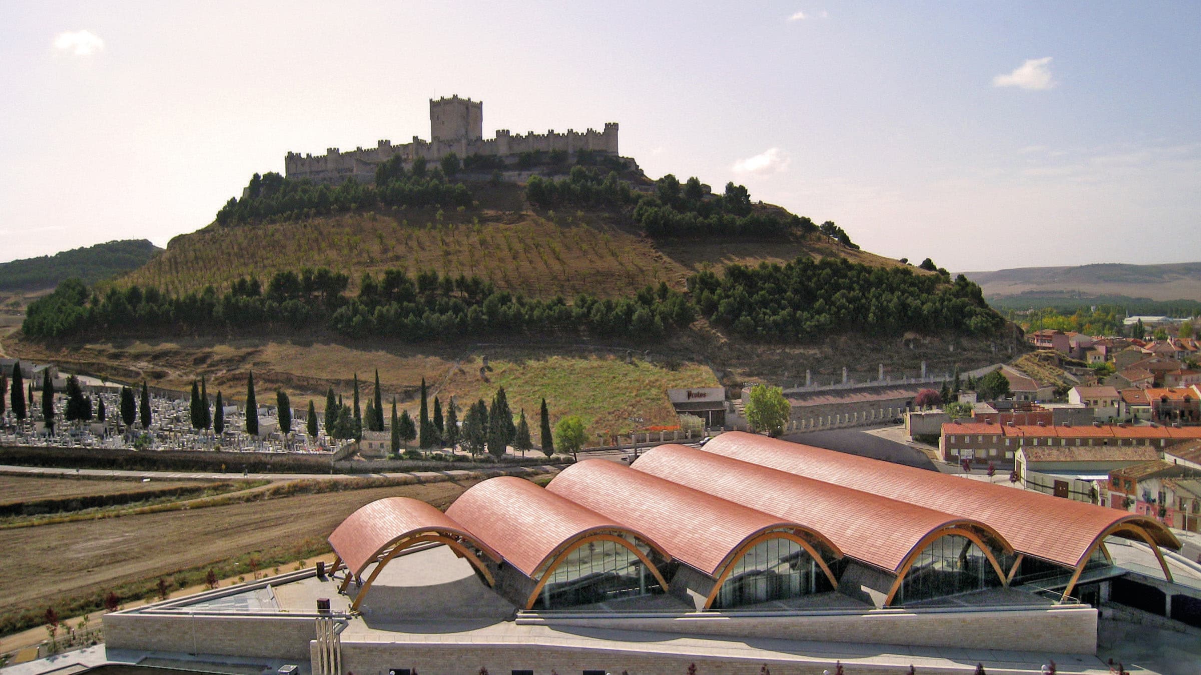 The five curved roofs of the Rogers building, with the Castle of Peñafiel behind